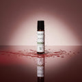 Oh Canada Gifts Spot Dabber acne treatment in a roll-on bottle surrounded by water splashes on a reflective surface.