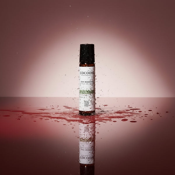 Oh Canada Gifts Spot Dabber acne treatment in a roll-on bottle surrounded by water splashes on a reflective surface.