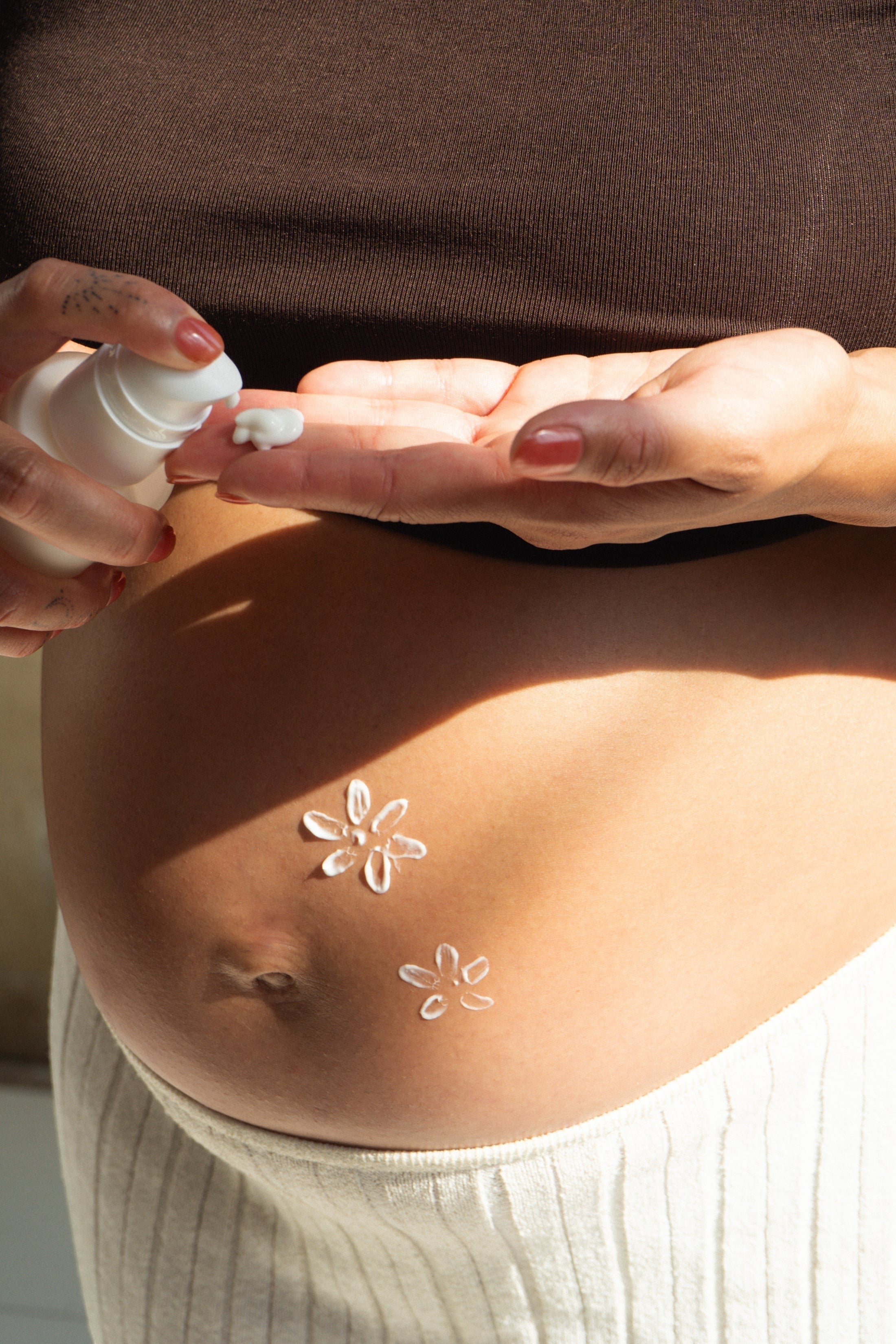 Oh Canada Gifts stretch mark cream applied to a pregnant belly with flower-shaped dots of lotion for skin care