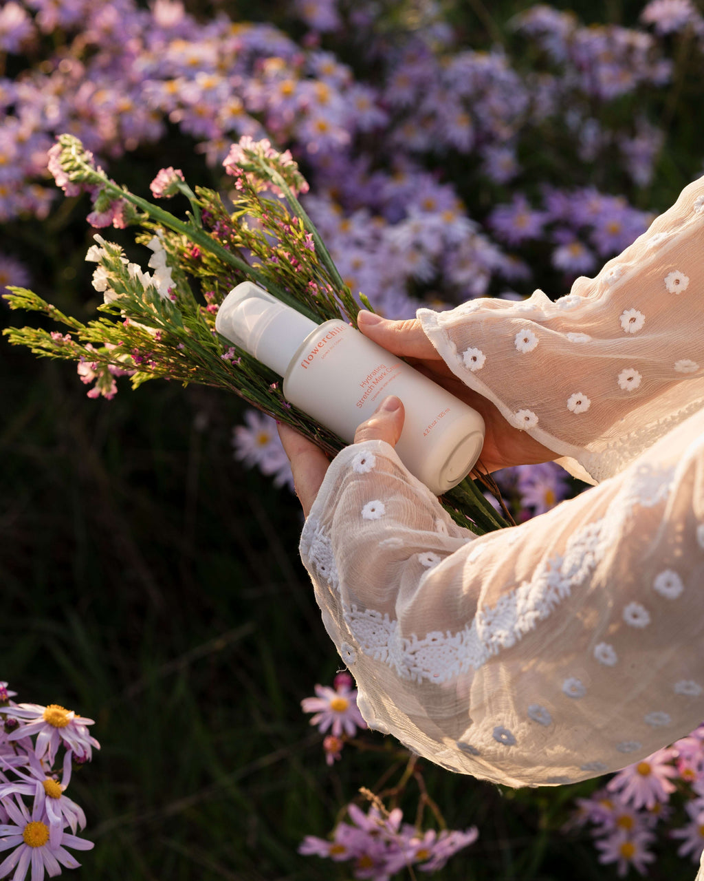 Oh Canada Gifts Flowerchild stretch mark cream held by hands in a floral field, promoting pregnancy skin care.