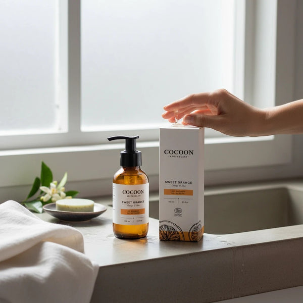 Oh Canada Gifts Cocoon Apothecary Sweet Orange Gel Cleanser bottle and box on a bathroom counter with a hand pressing pump