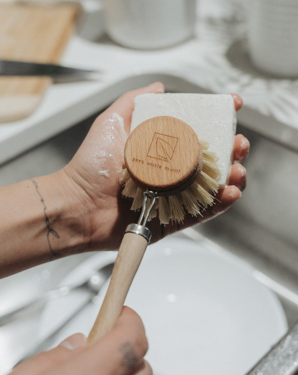 Oh Canada Gifts unscented solid dish soap bar held in hand with a wooden dish brush for zero waste cleaning