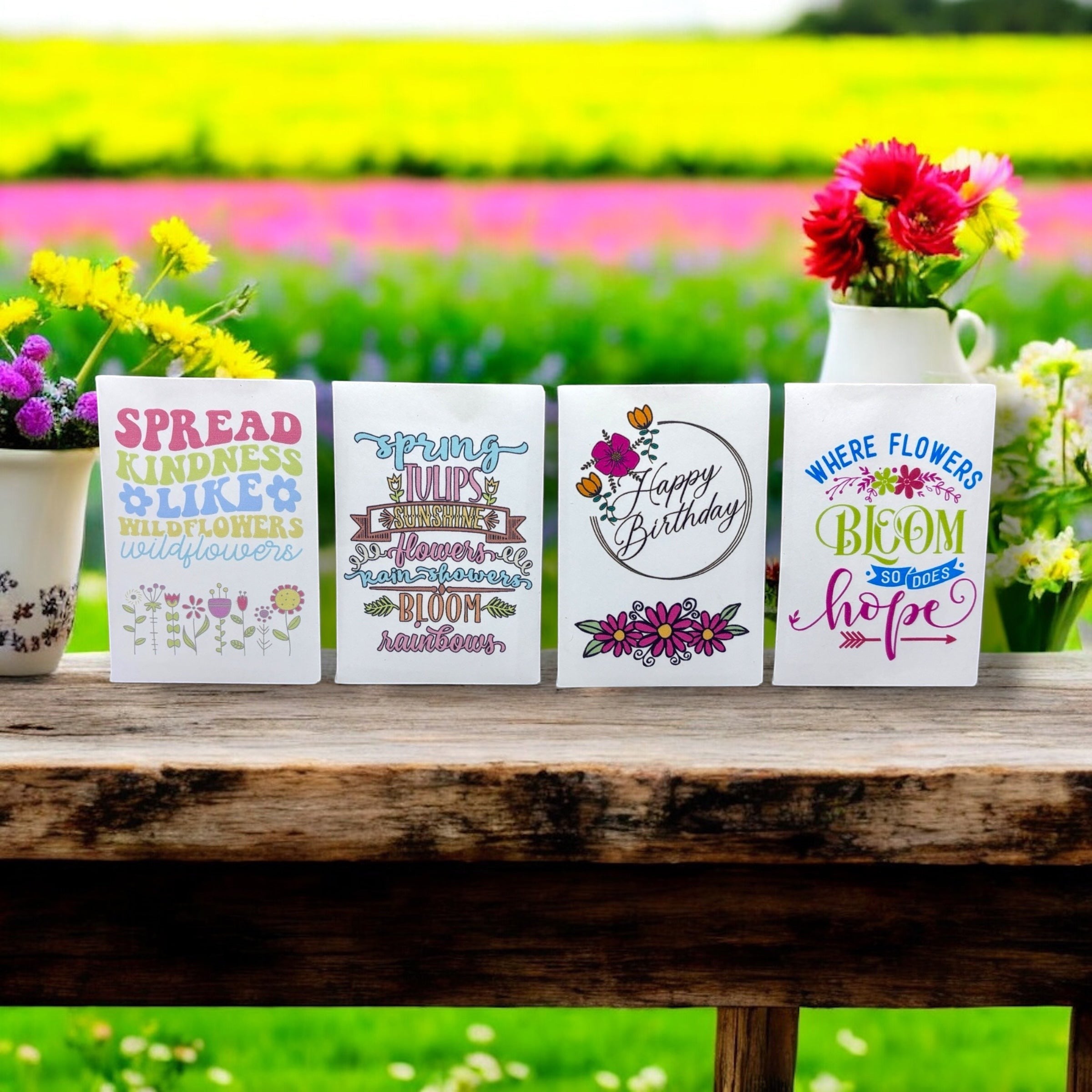 Oh Canada Gifts wildflower seed packages with colorful floral designs displayed on a wooden table in a garden.