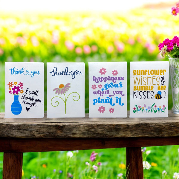 Oh Canada Gifts wildflower seed packages with colorful floral designs and messages on a rustic wooden bench.