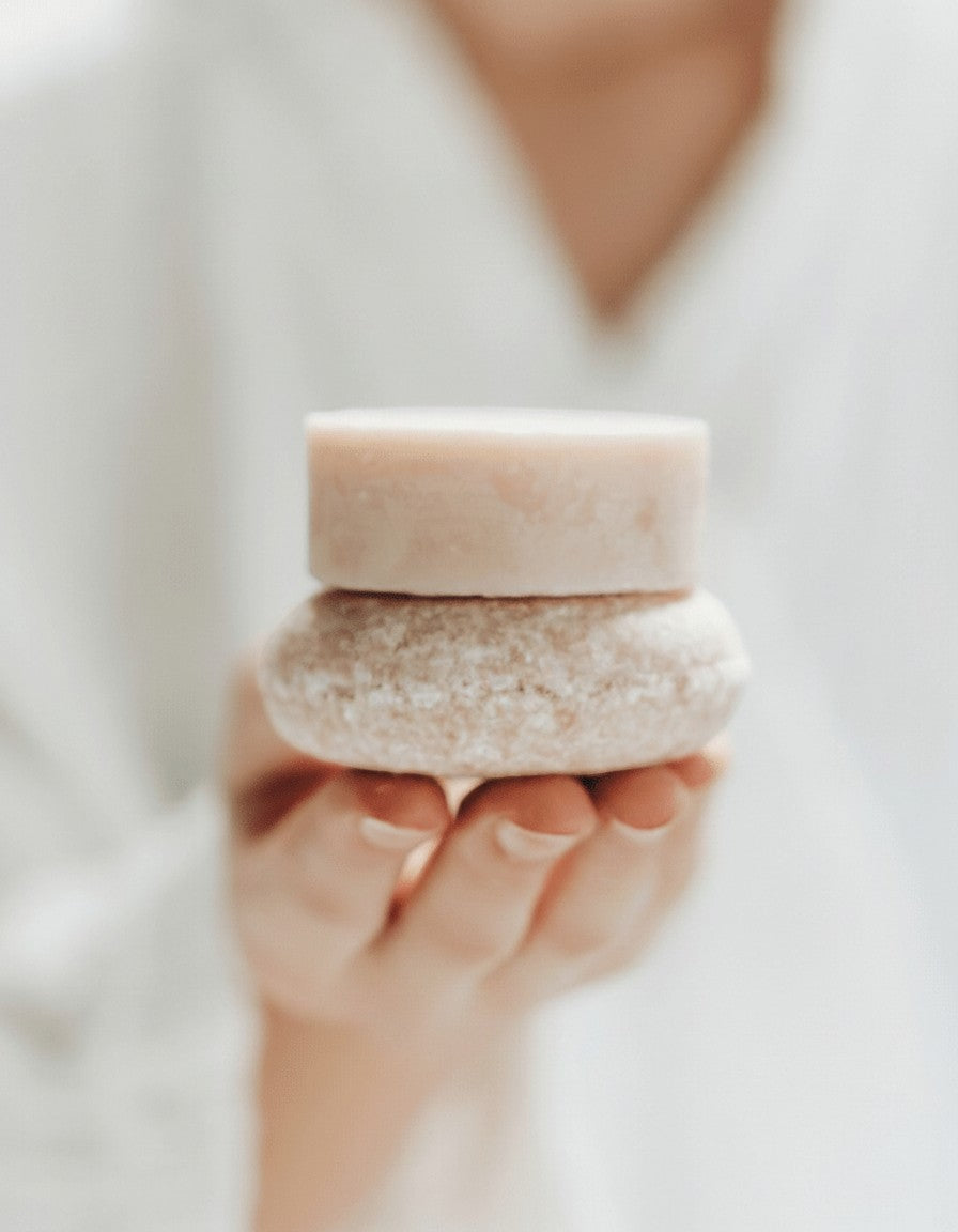 Oh Canada Gifts zero-waste shampoo and conditioner bar duo held in a hand for a sustainable hair care routine